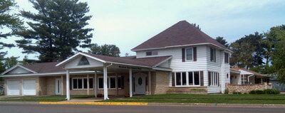 A large white house with a red roof is sitting on the side of the road.