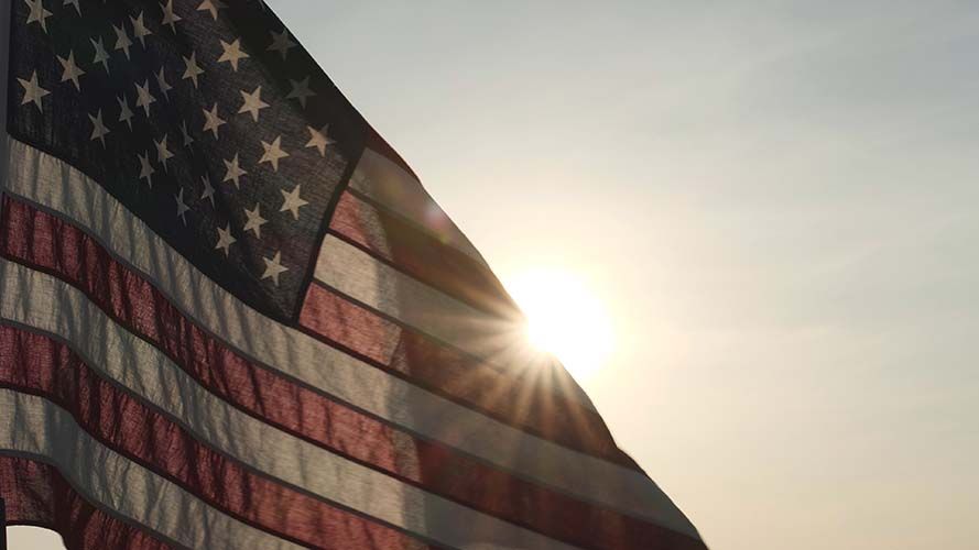 A woman is putting her hand on an american flag at a funeral.