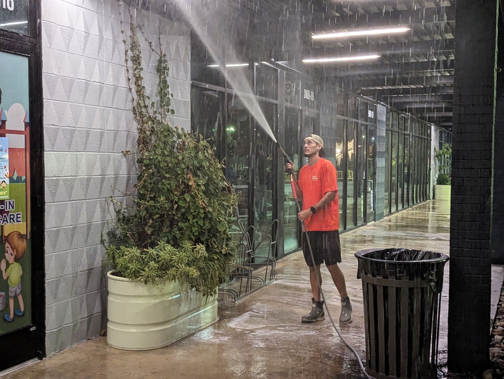 A man is cleaning a building with a hose.