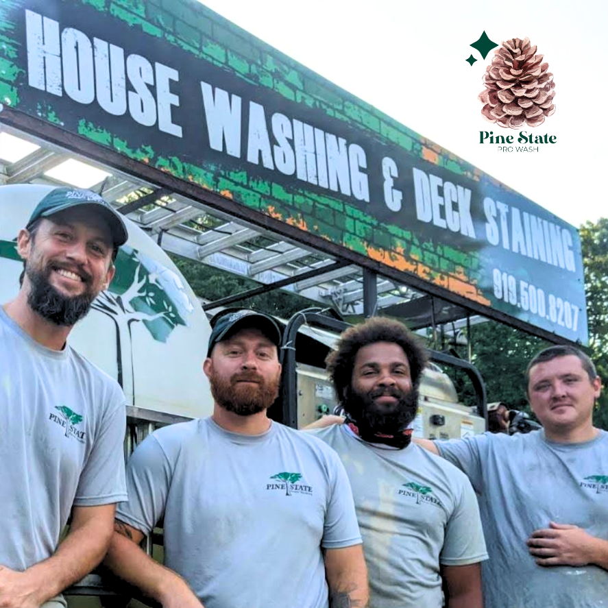 Four smiling crew members in gray branded shirts stand before a Pine State Pressure Washing truck.