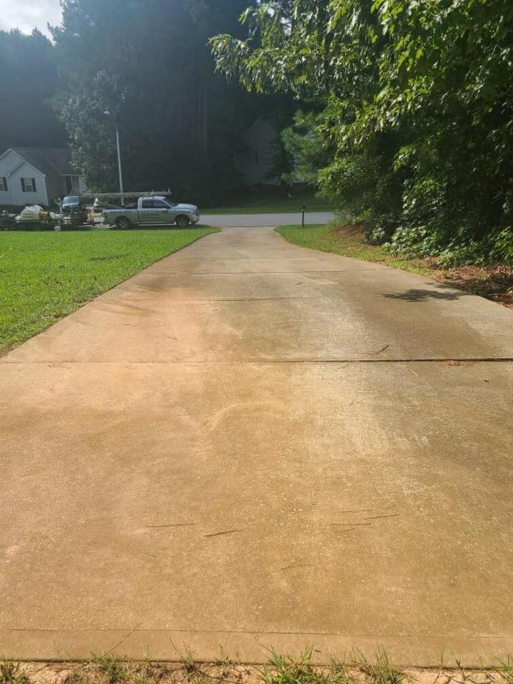 A concrete driveway leading to a house with cars parked on the side of it.