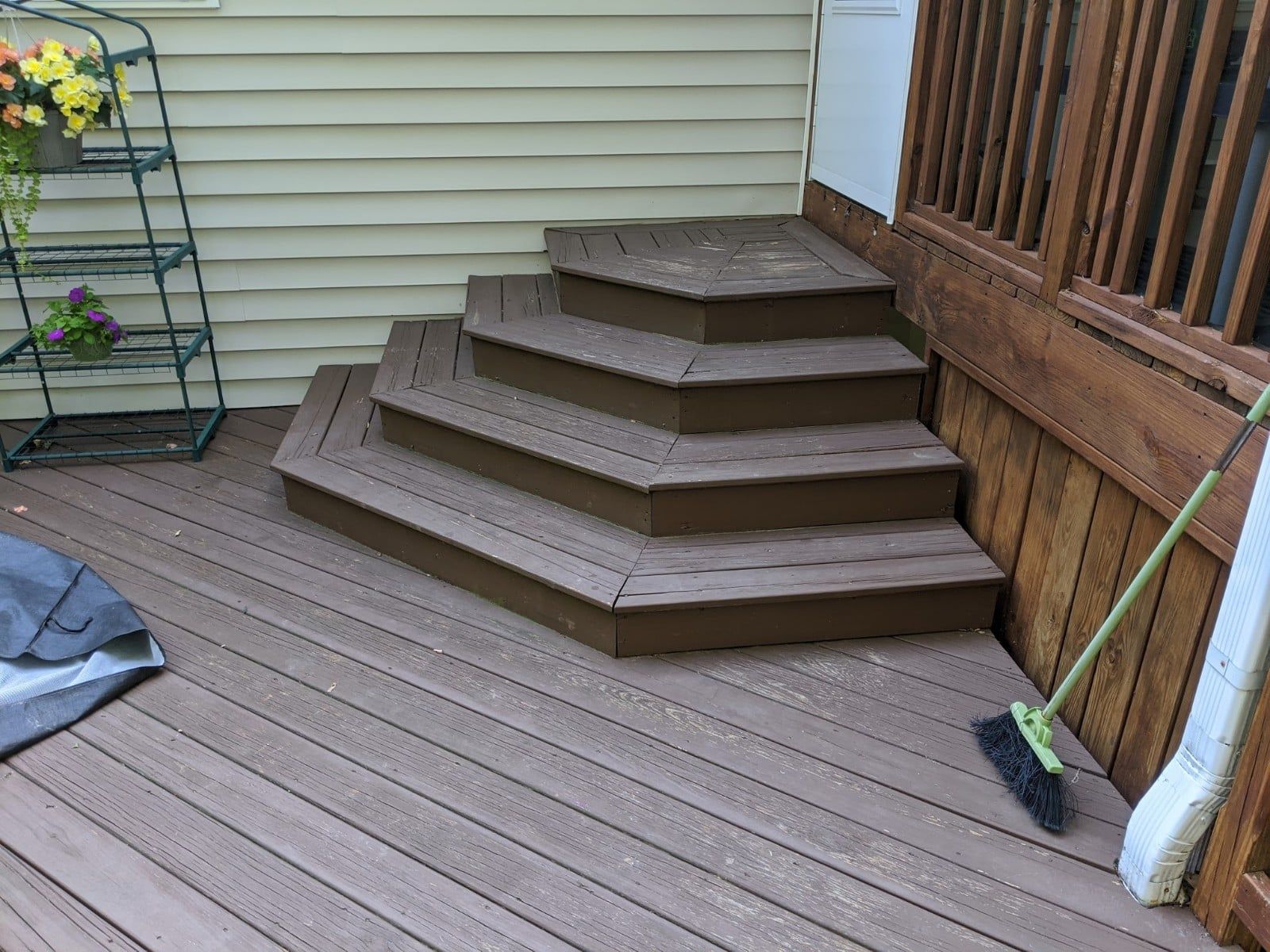 A wooden deck with stairs and a broom on it.