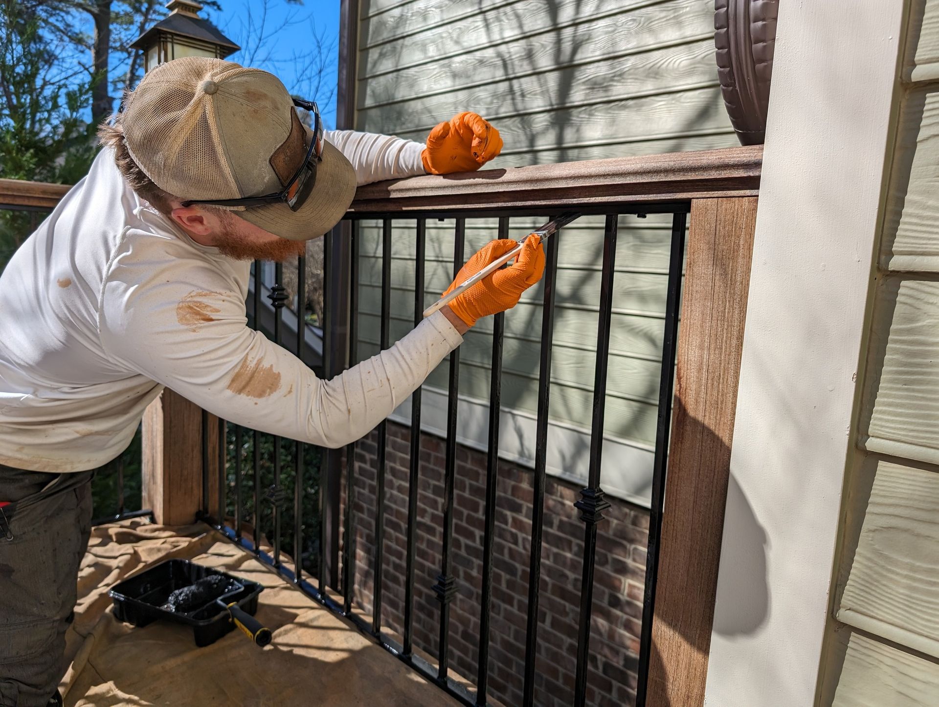 A man is painting a railing on a deck.