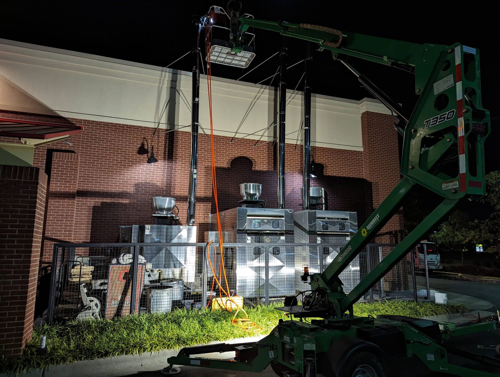 A man is standing on a lift in front of a building at night.