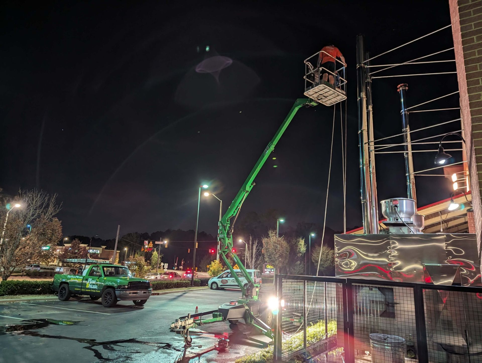 A green crane is working on a building at night.