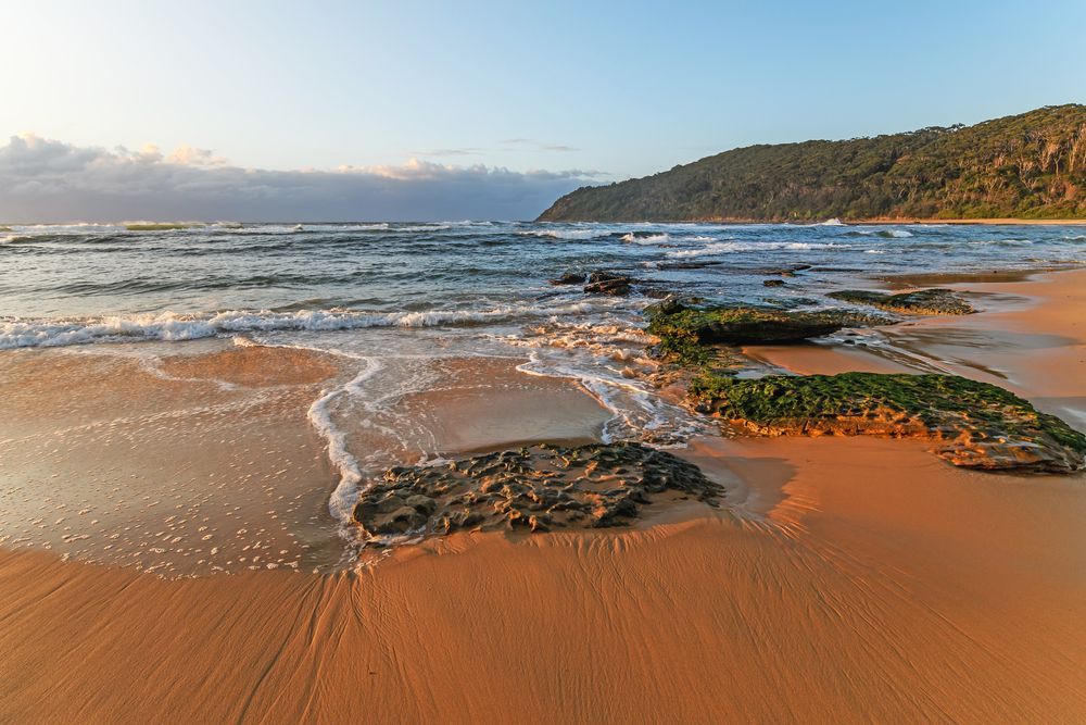 A Sandy Beach With Rocks in the Water — Coastal Automotive Services Long Jetty in Bateau Bay, NSW