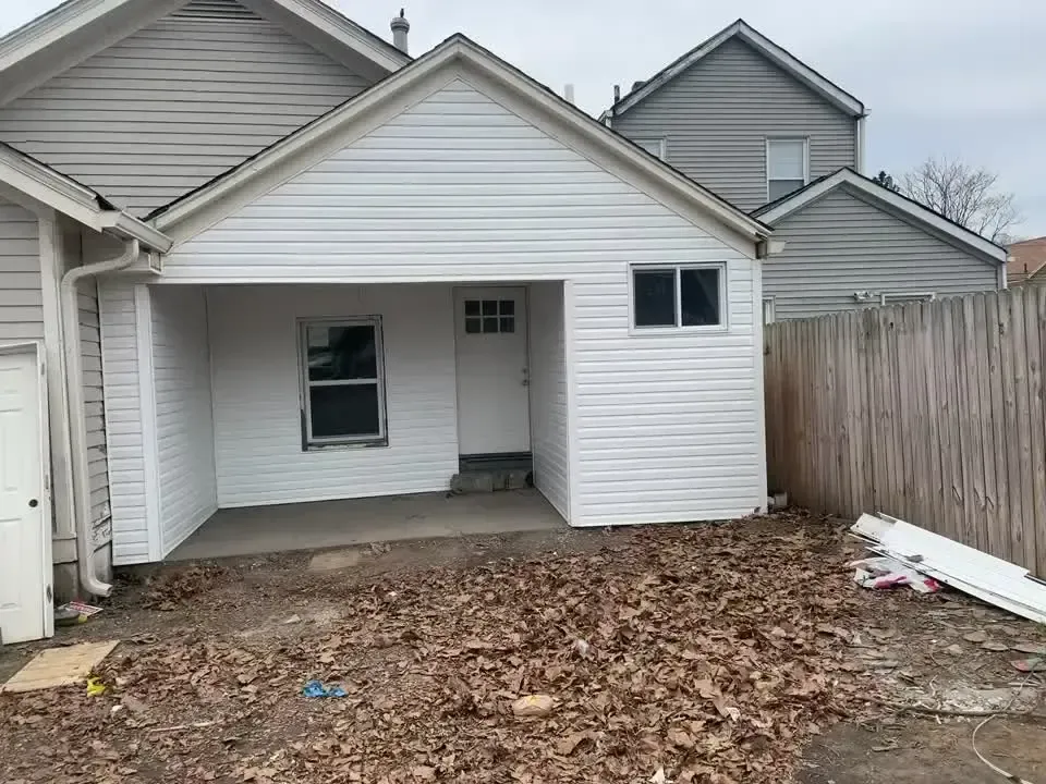 A white house with a garage and a fence in front of it.