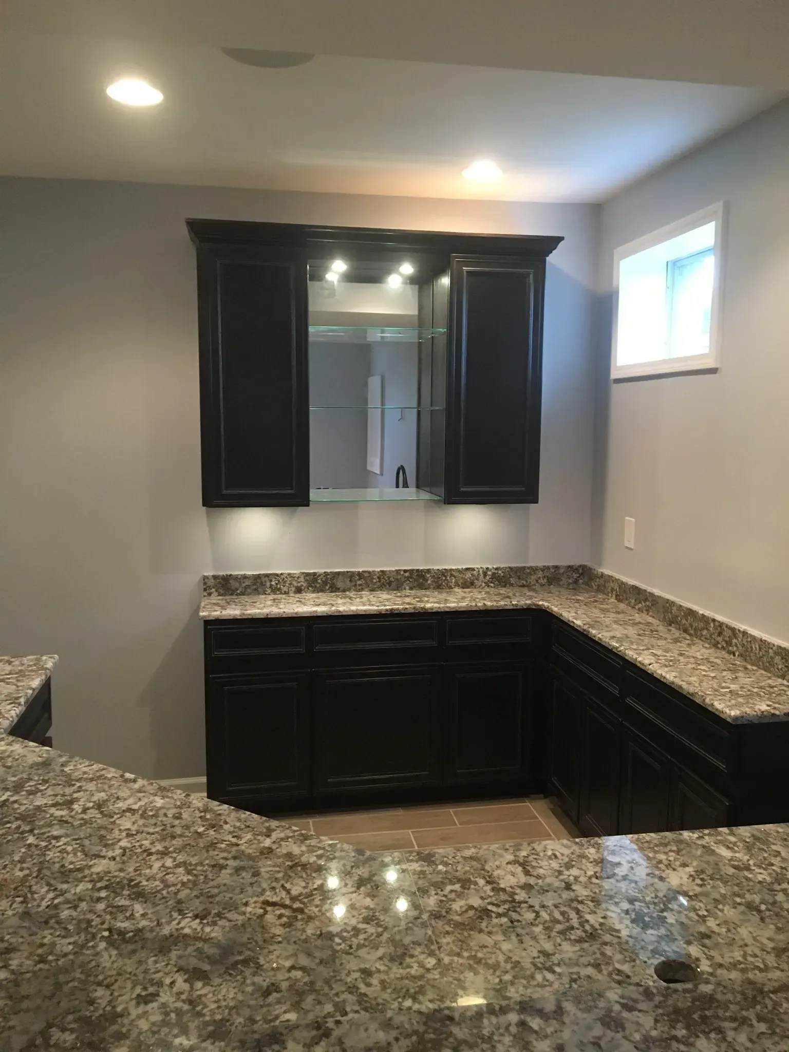 A kitchen with granite counter tops and black cabinets