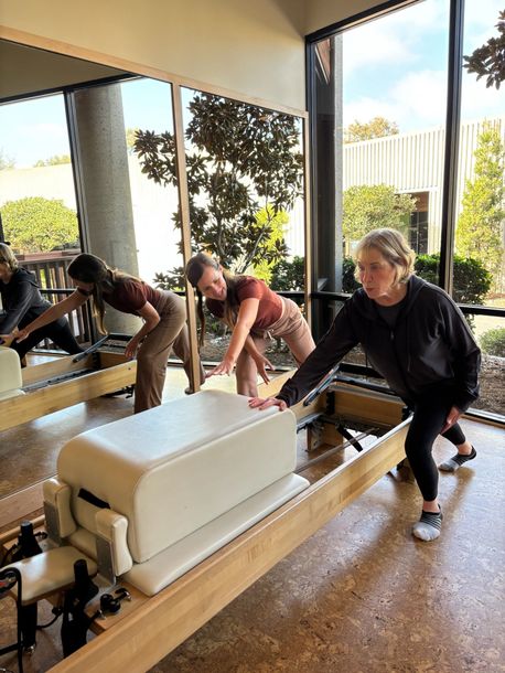 Private reformer Pilates machines in a bright studio with mirrors and large windows. Encintias