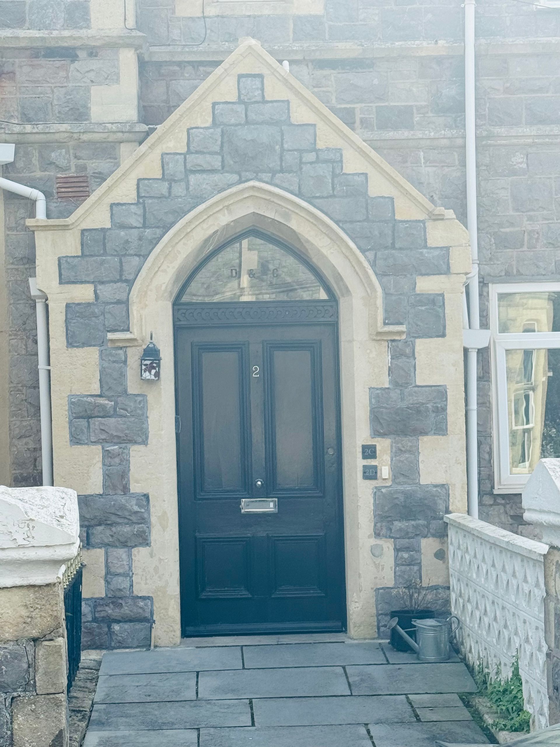 A brick building with a black door and a stone archway