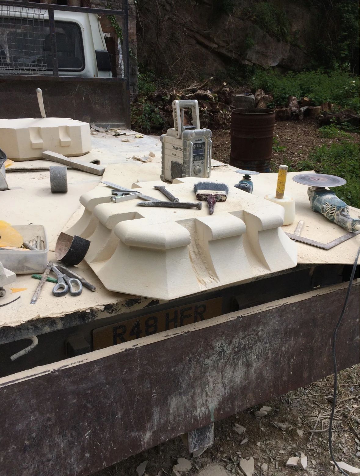 A table with a lot of tools on it and a truck in the background.