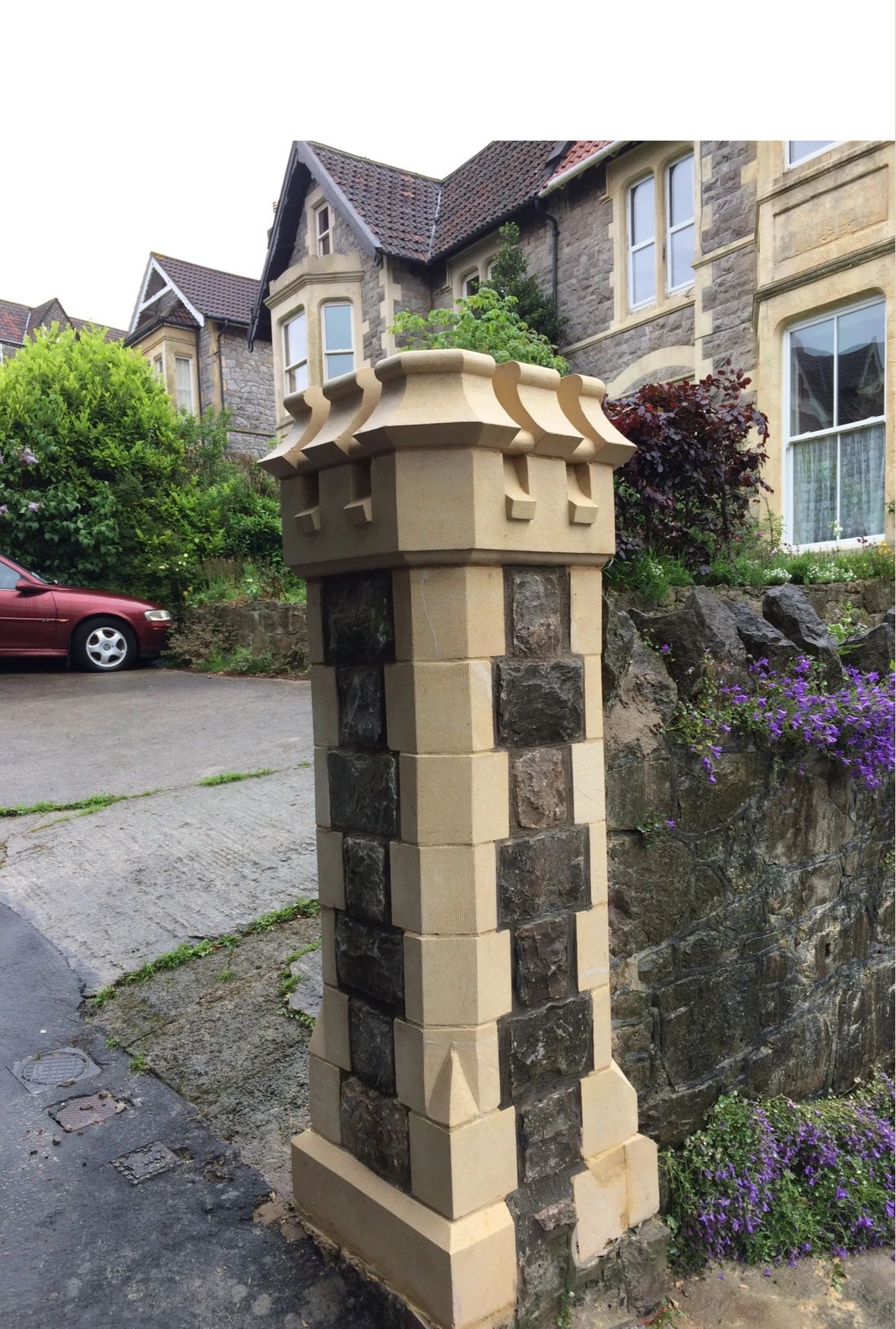 A stone column with a car parked in front of it.