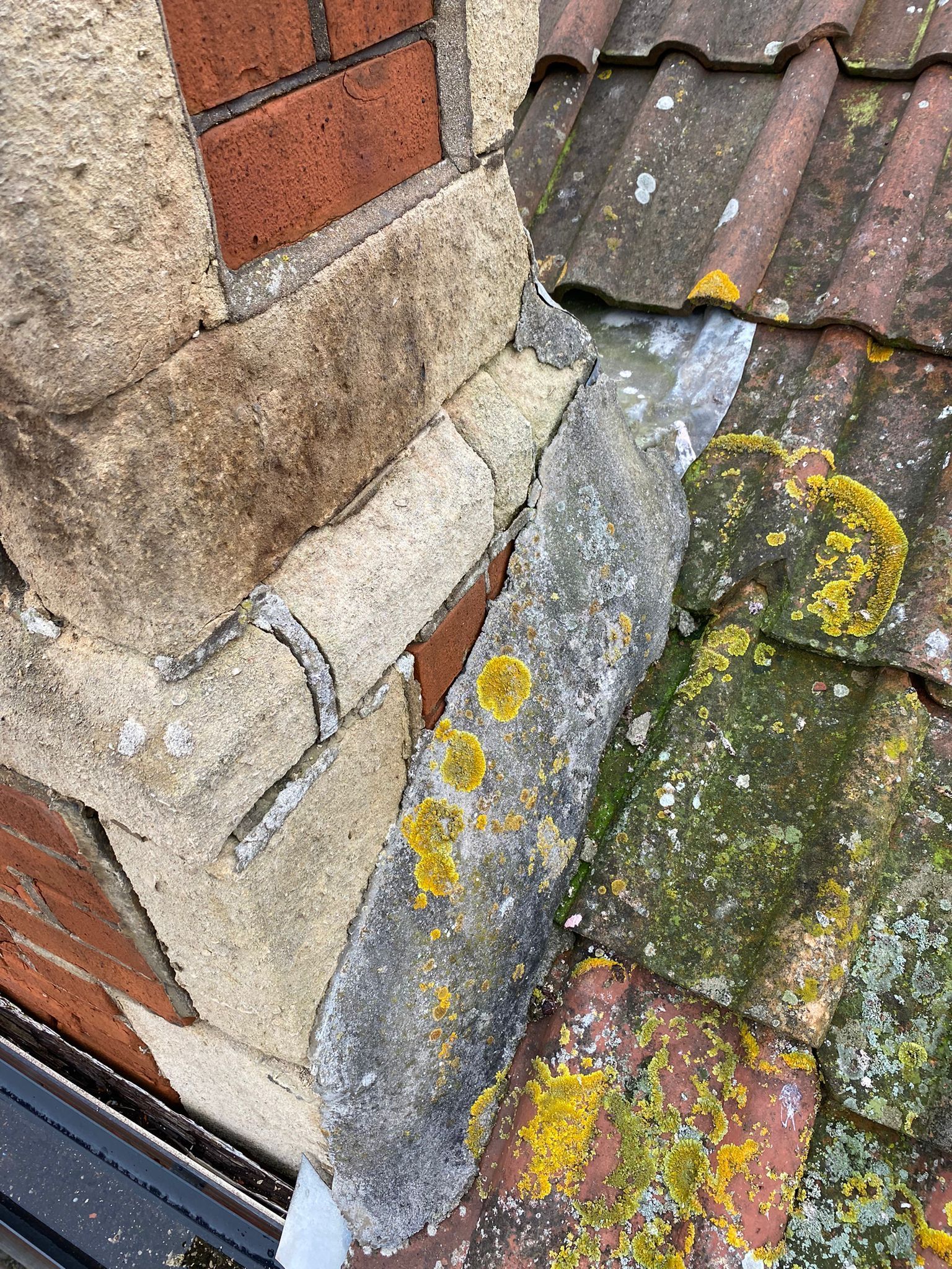 A close up of a gutter on a roof next to a brick wall.