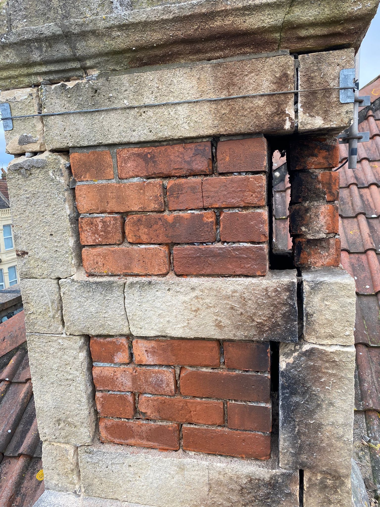 A brick chimney on top of a roof with a hole in it.