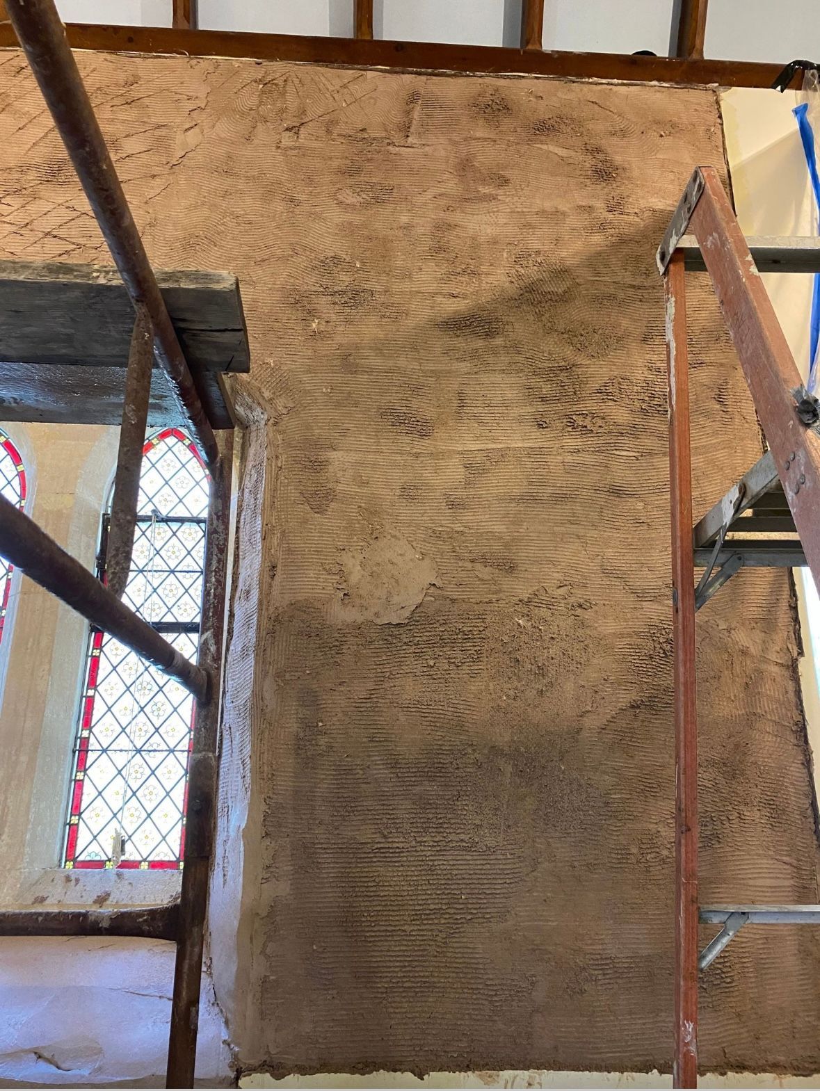 A ladder is sitting on top of a wall next to a window.
