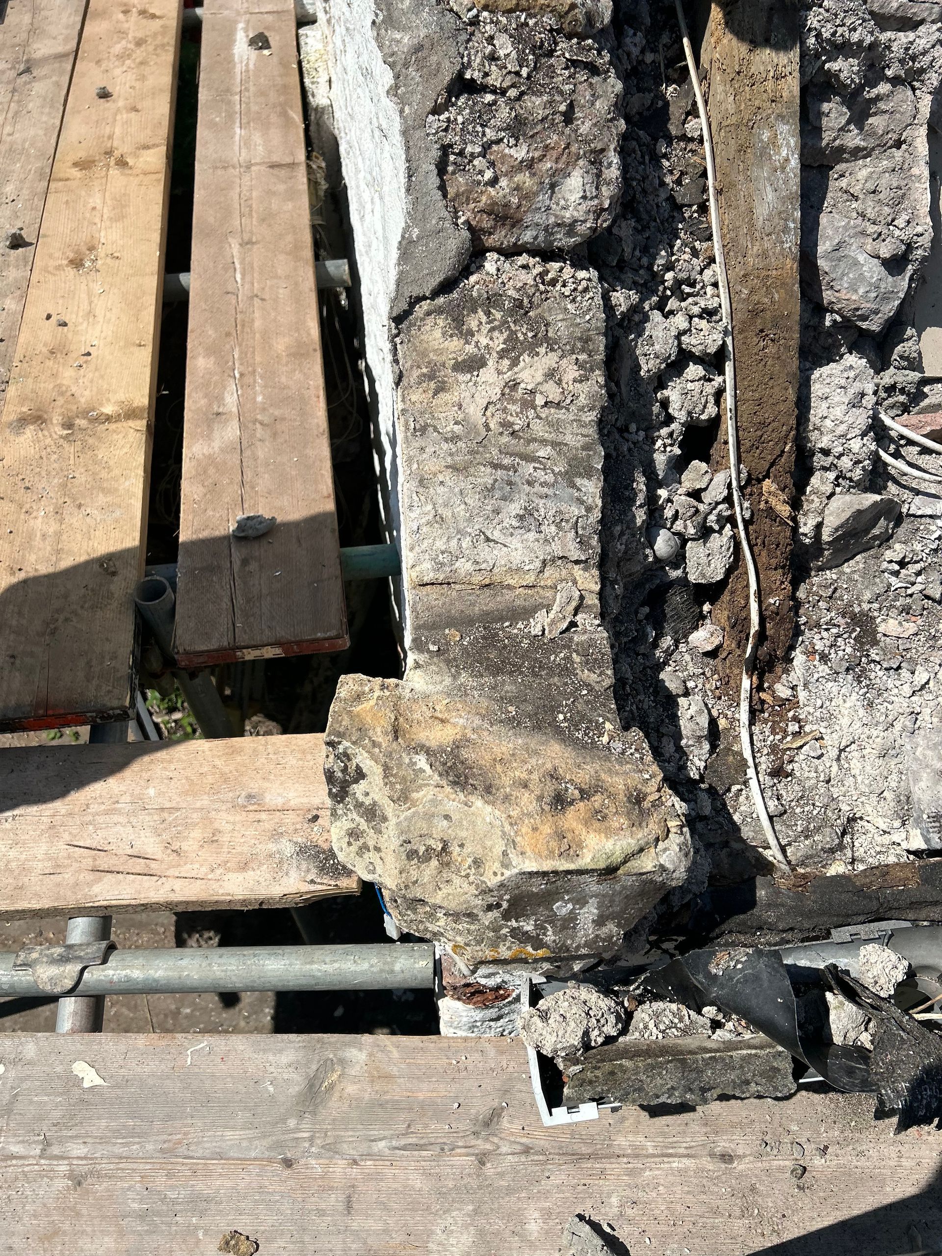 A wooden plank is sitting next to a stone wall.