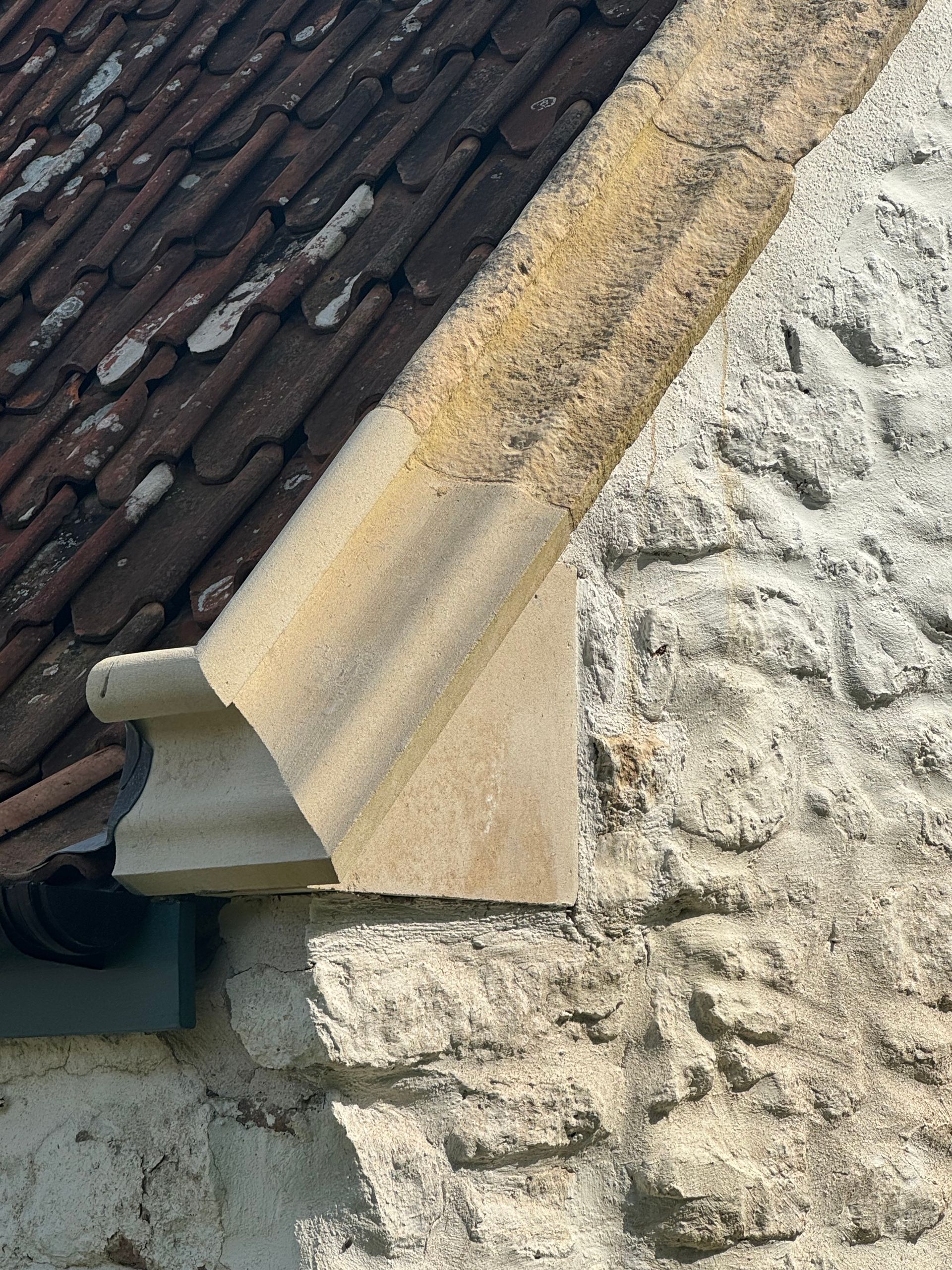 A close up of a stone wall with a roof in the background
