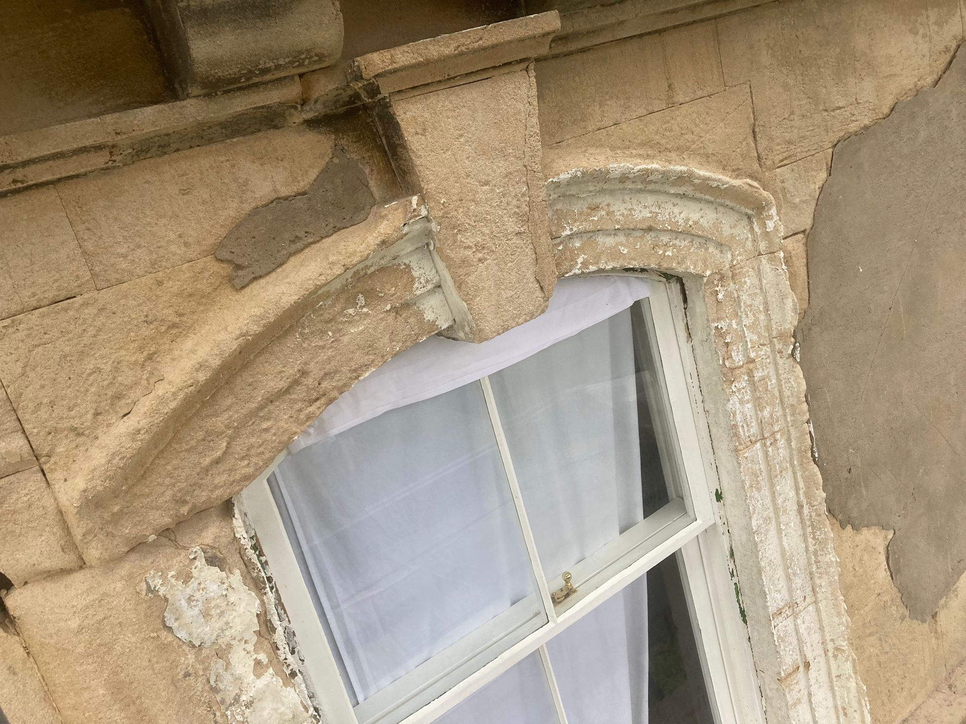 A window on the side of a building with a white curtain.
