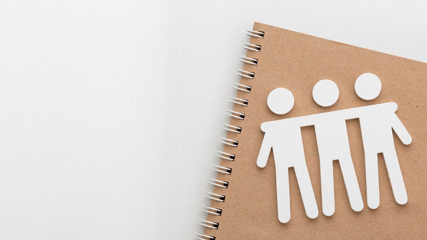 Tres personas de papel están paradas una al lado de la otra en un cuaderno de espiral.