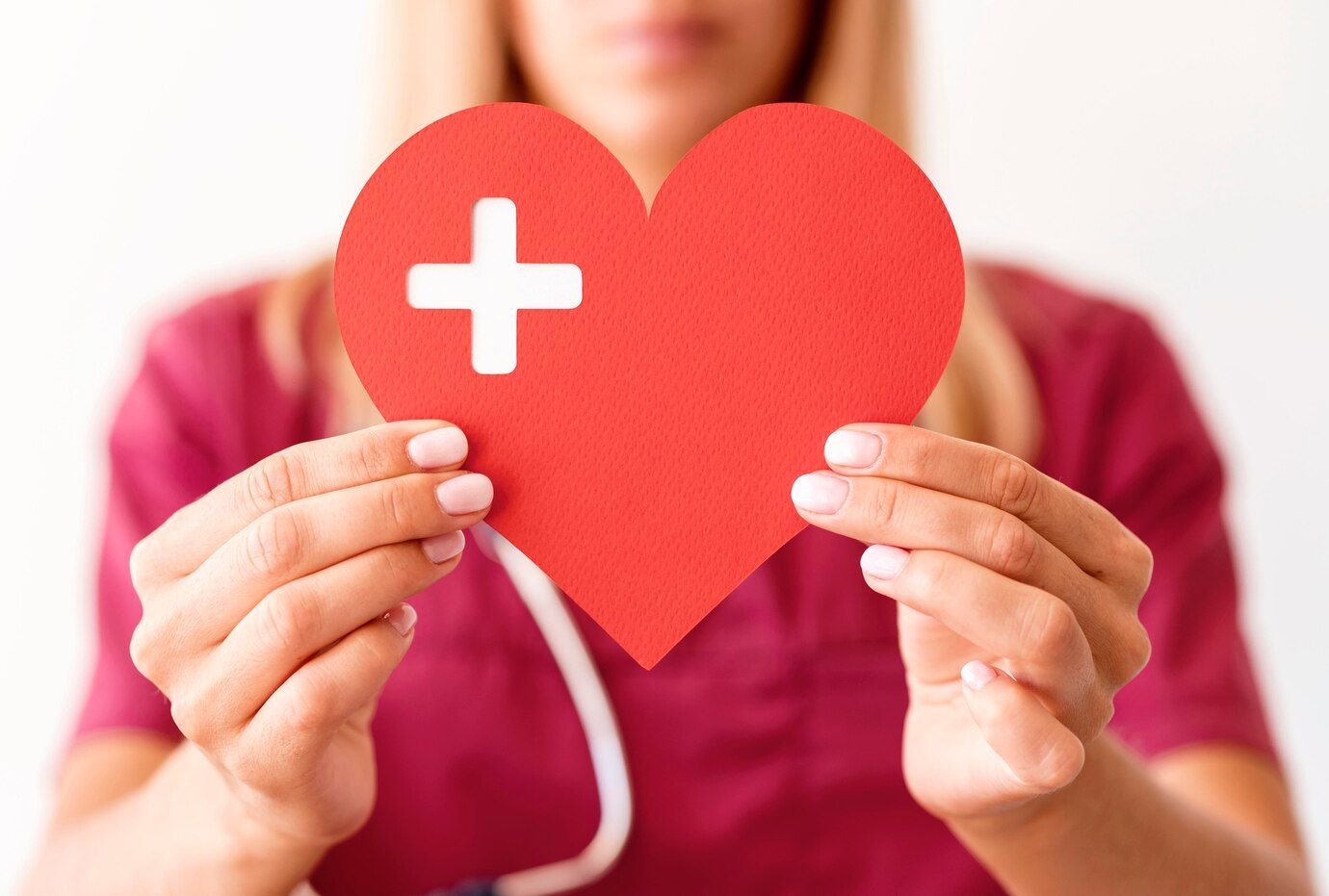 Una mujer sostiene un corazón rojo con una cruz blanca.