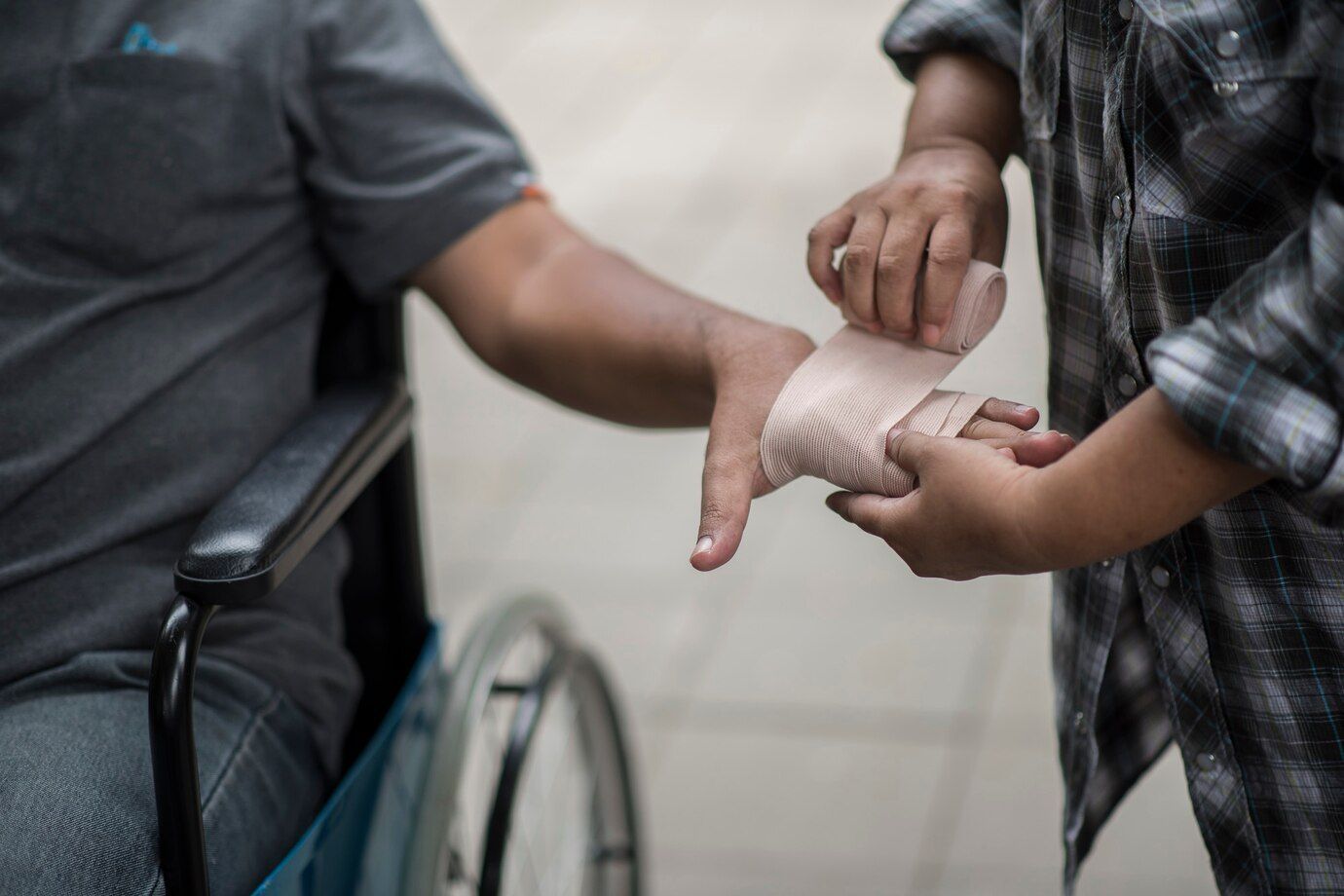 A una persona en silla de ruedas le están vendando la mano.