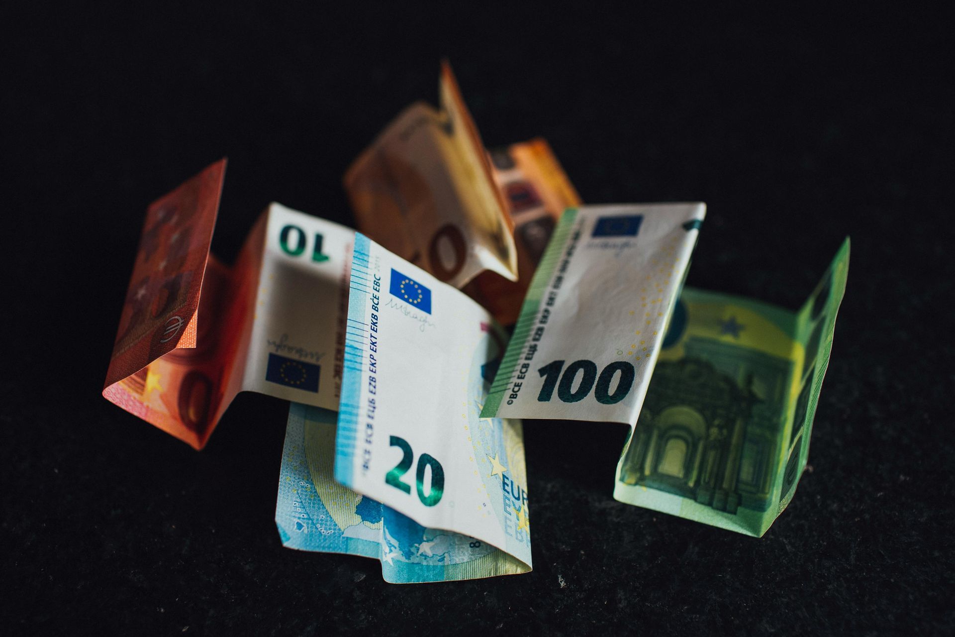 Billetes de euro de diversas denominaciones, desplegadas en abanico, sobre un fondo oscuro.