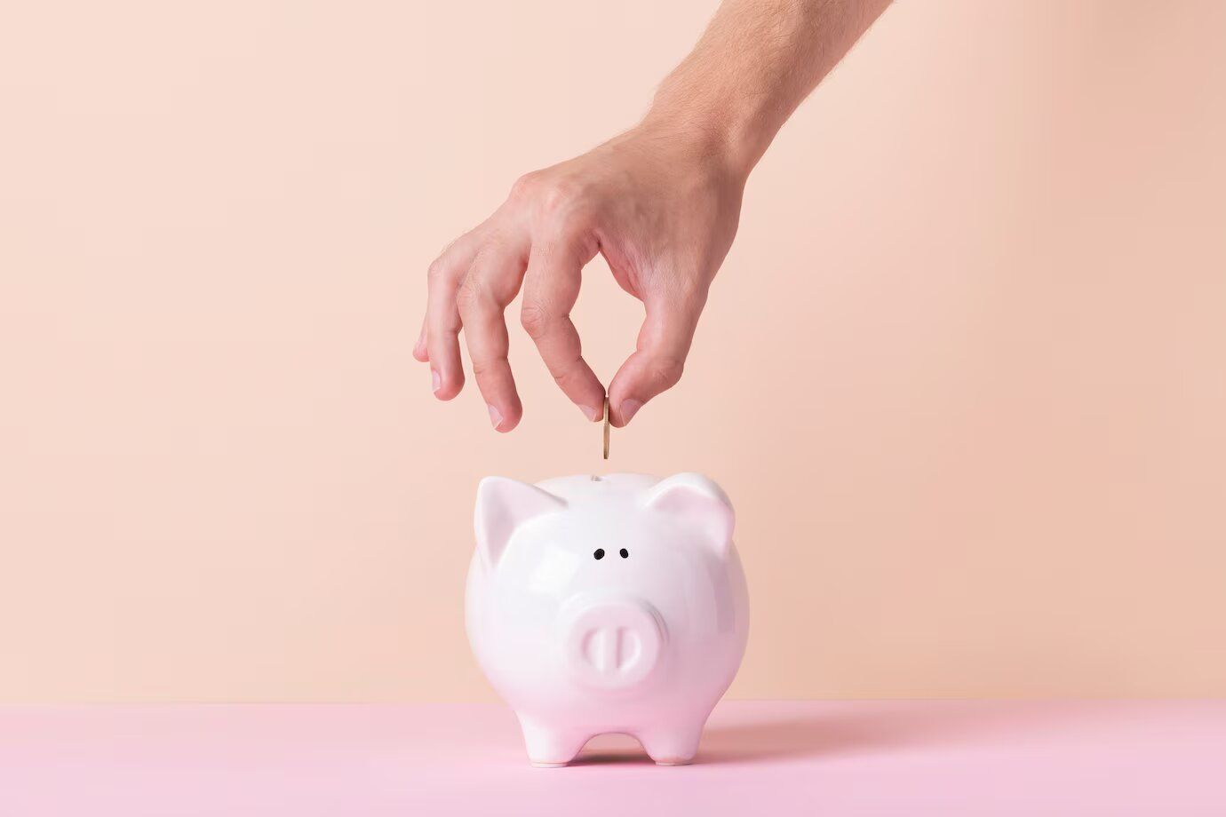 Una persona está poniendo una moneda en una alcancía.