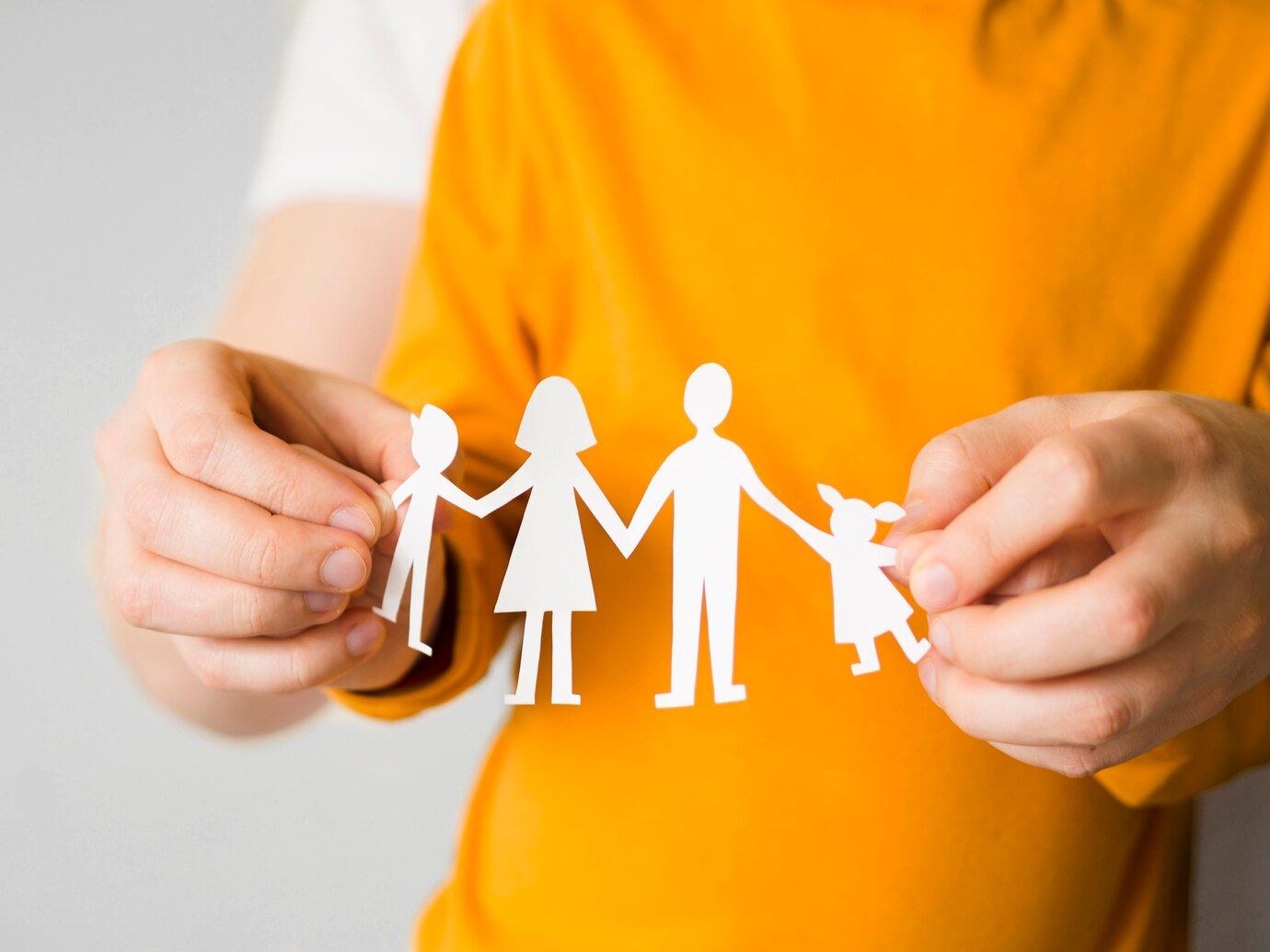 Una persona sostiene un papel recortado de una familia.
