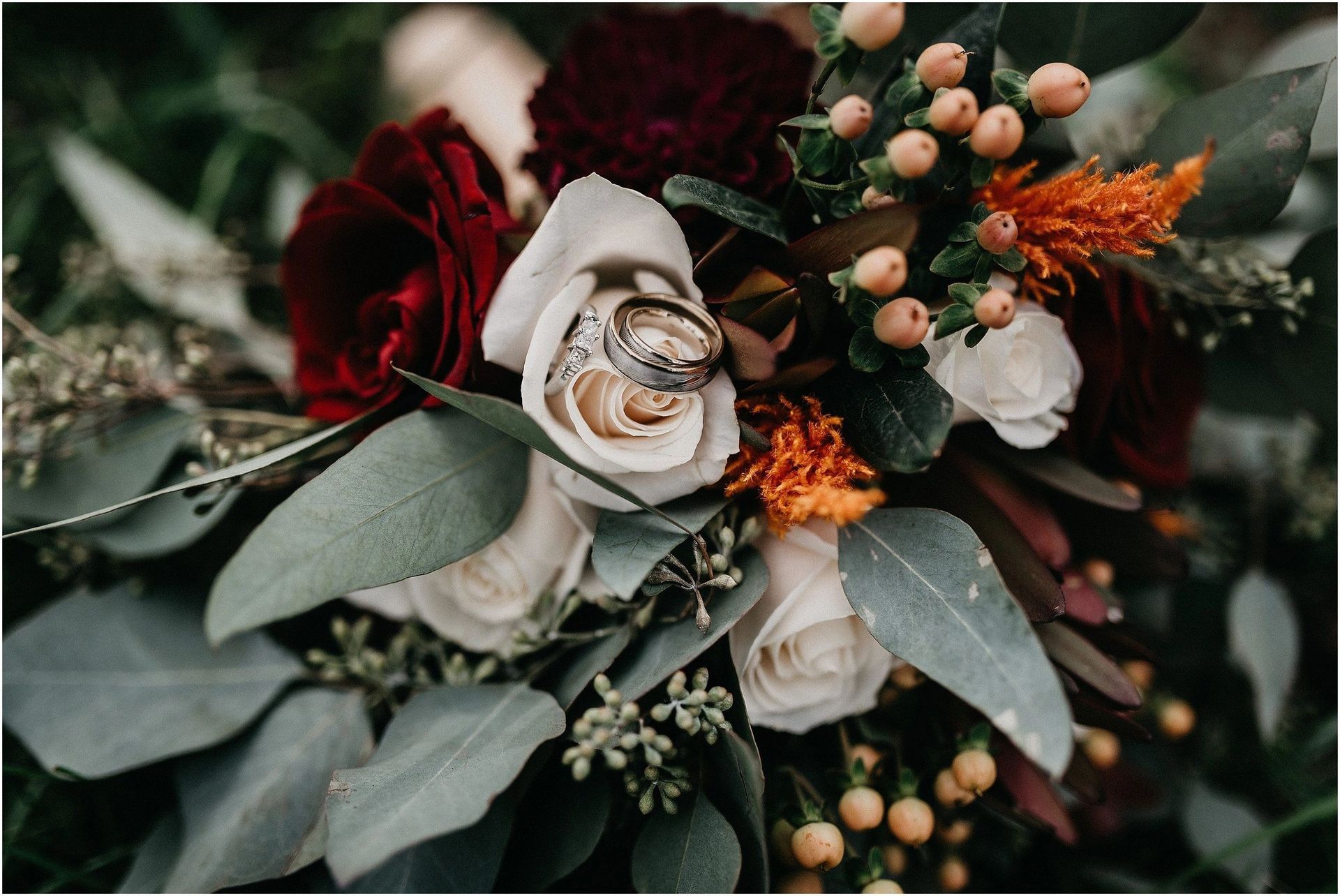 A close up of a bouquet of flowers with wedding rings on them.