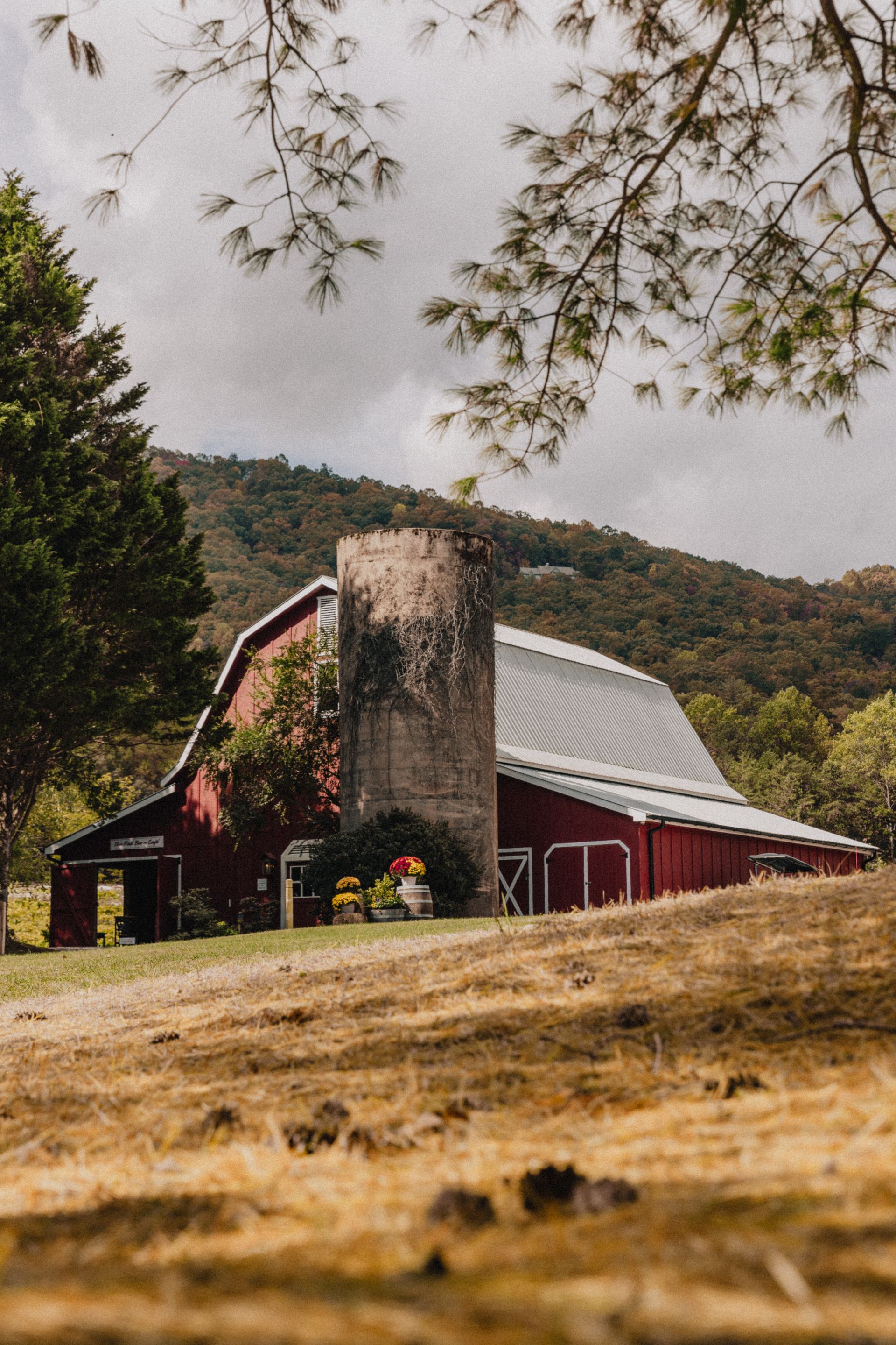 A red barn with a silo in the middle of a field.