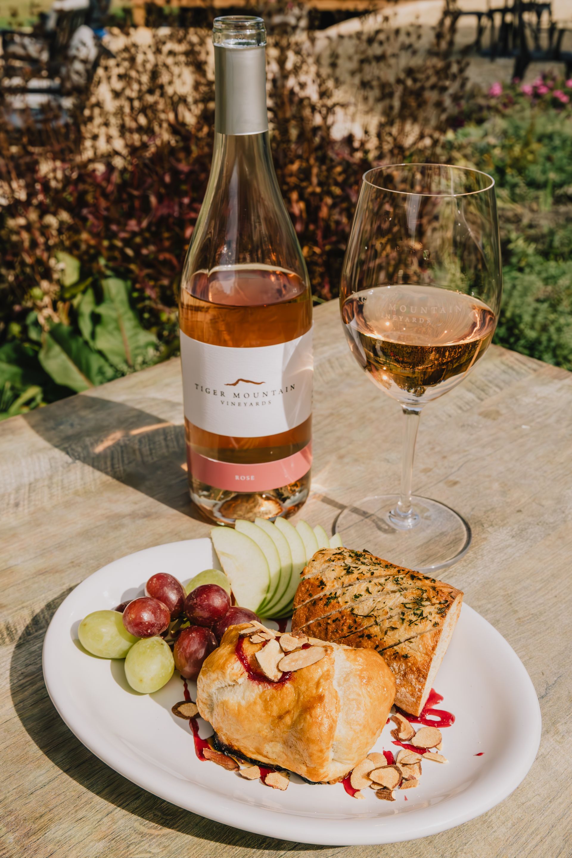 A bottle of wine and a glass of wine are on a table next to a plate of food.