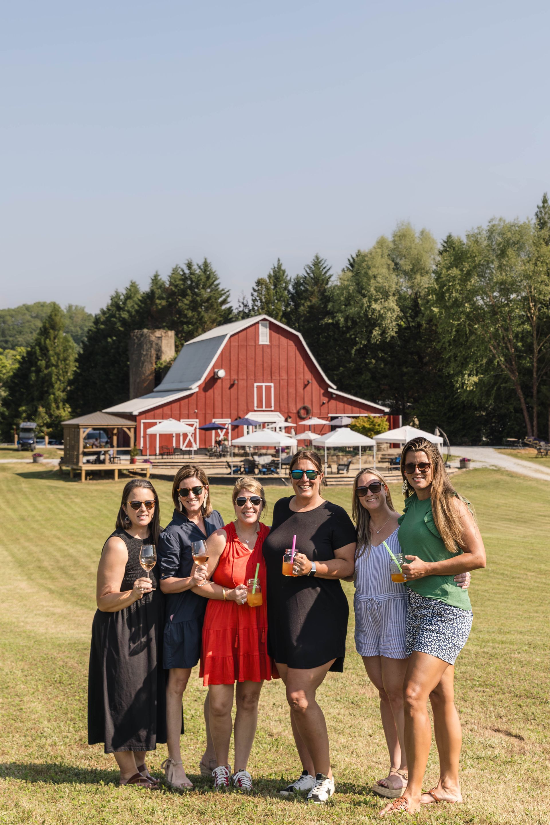 A group of women are posing for a picture in front of a red barn.