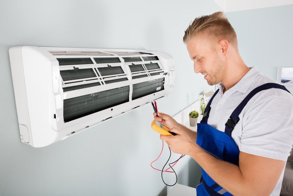 Male Electrician Checking Air Conditioner With Digital Multimeter — Air Conditioning in Basin View NSW