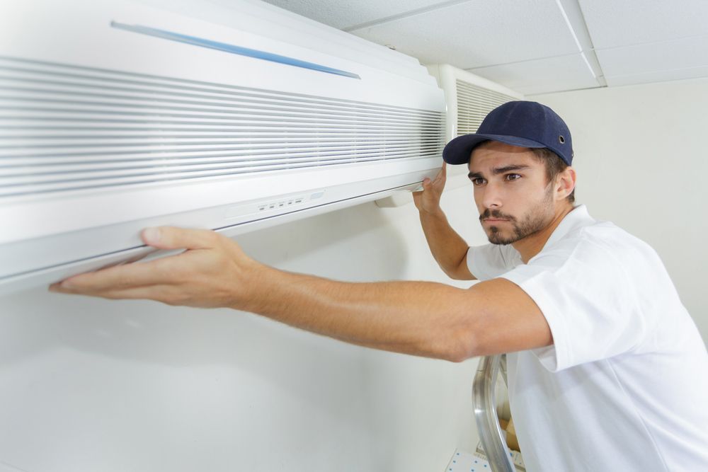 Skilled Person Installing new Air Conditioner System on Wall — Air Conditioning Repairs in Vincentia NSW
