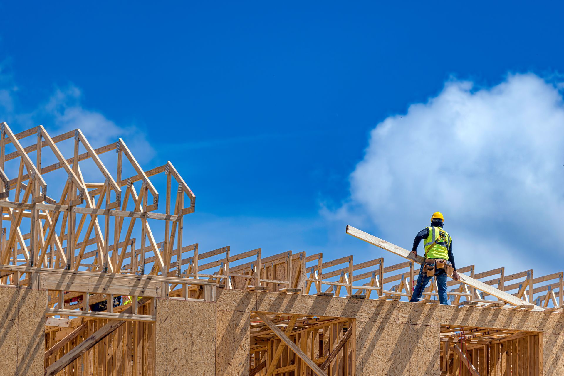 A worker is holding a wooden plank on a house under construction.