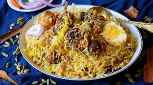 Plate of biryani rice topped with boiled eggs, surrounded by onions and herbs on a blue background