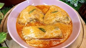 Three fried fish pieces in orange sauce on a pink plate