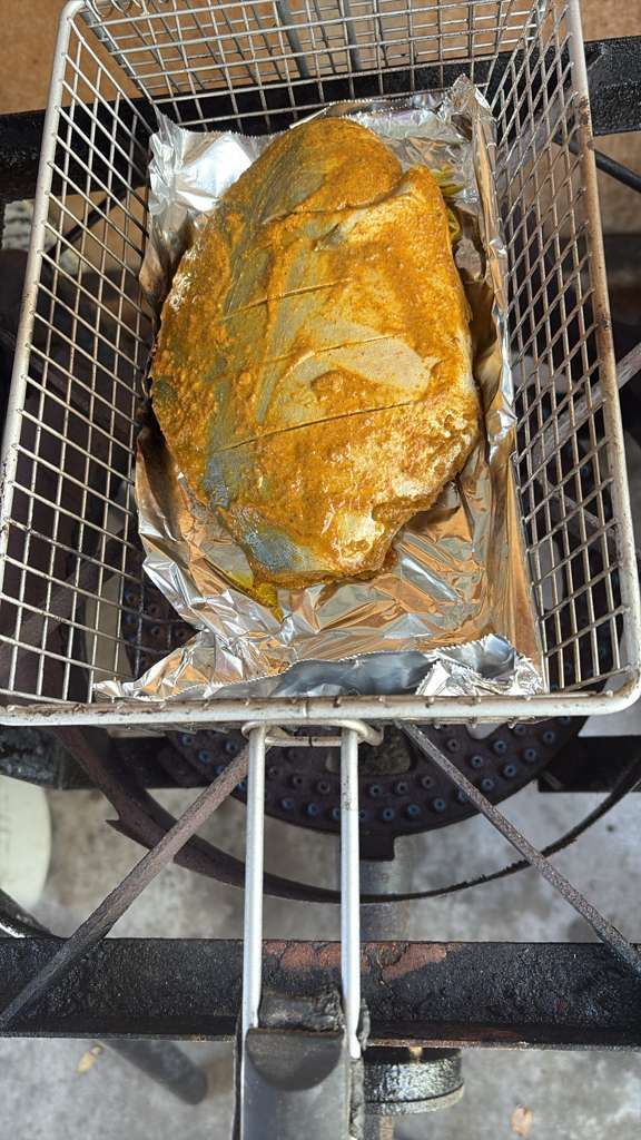 Seasoned roast in a foil-lined grill basket over a charcoal barbecue, viewed from above