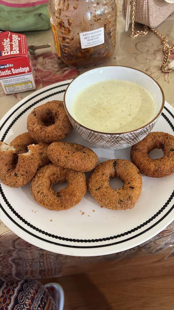 Plate of cinnamon sugar donuts with a bowl of cream-colored dipping sauce on a table