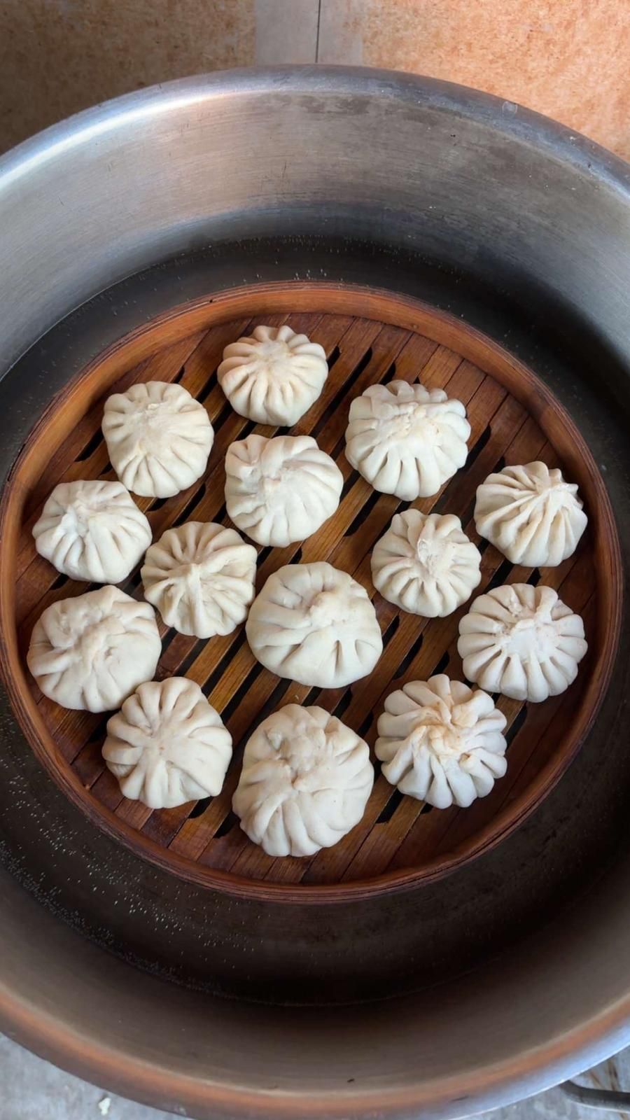 Steamed dumplings arranged in a bamboo basket inside a metal steamer pot