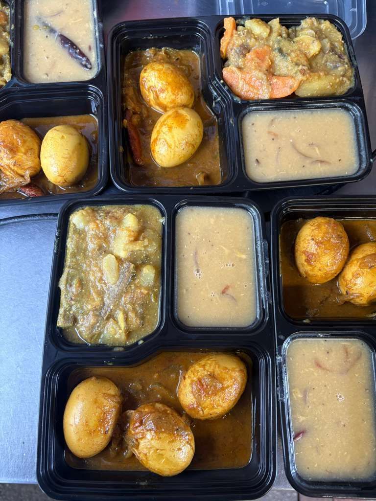 Assorted Indian meal trays with curries, rice, and small potatoes in compartmentalized containers