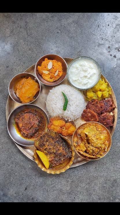 Indian thali with rice, curries, fried snacks, yogurt, and pickle on a metal plate