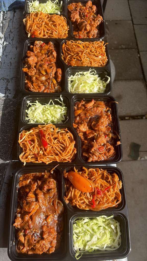 Takeout meal containers with assorted sauced dishes and shredded cabbage on a sidewalk.