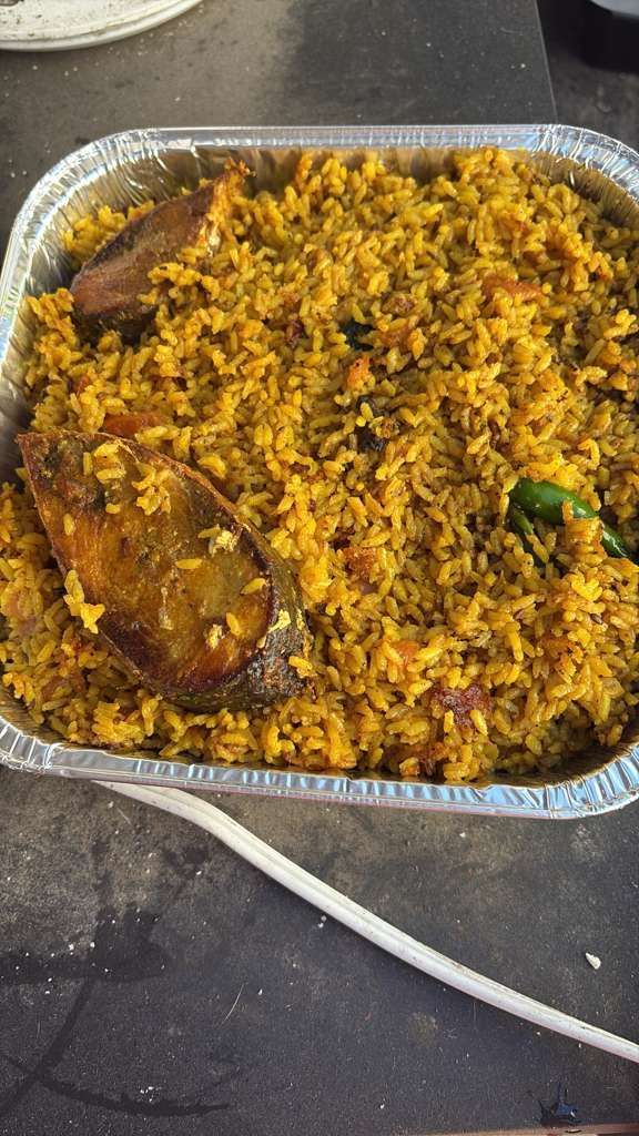 Tray of yellow rice with chicken pieces and a green chili pepper, served in a foil pan on a countertop