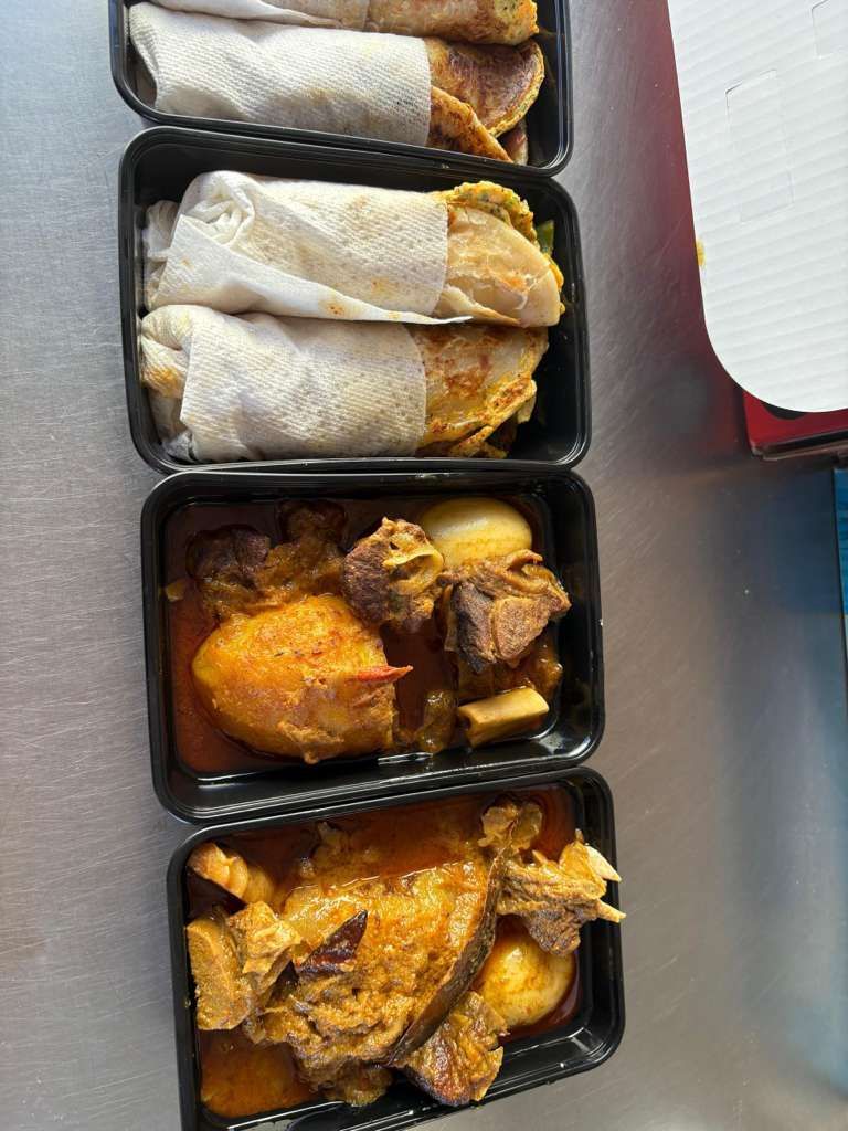 Takeout meal with wrapped wraps and two trays of orange chicken or curry-like dish