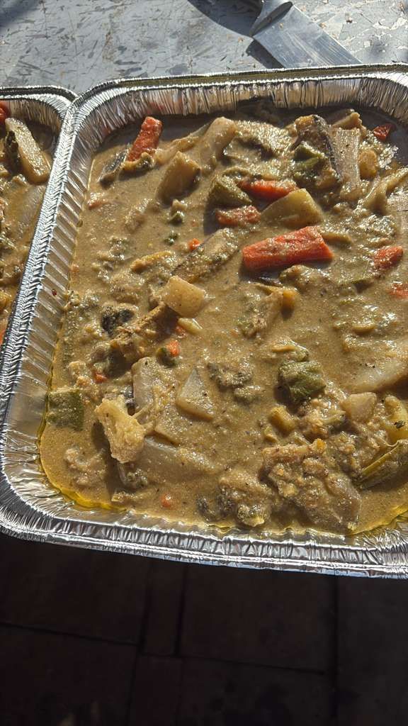 Tray of creamy stew with vegetables and red peppers in an aluminum pan.
