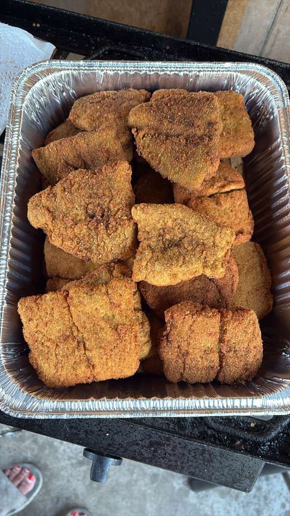 Foam tray of breaded fried food pieces, golden-brown and stacked on a countertop.