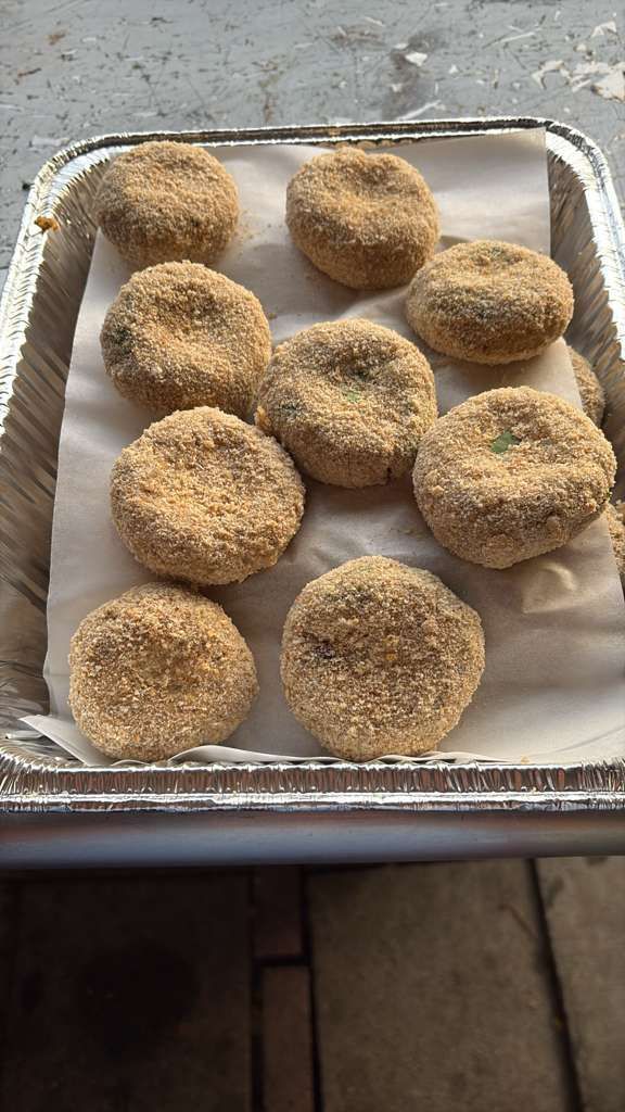 Tray of breaded dough rounds arranged on parchment paper, ready to be baked.