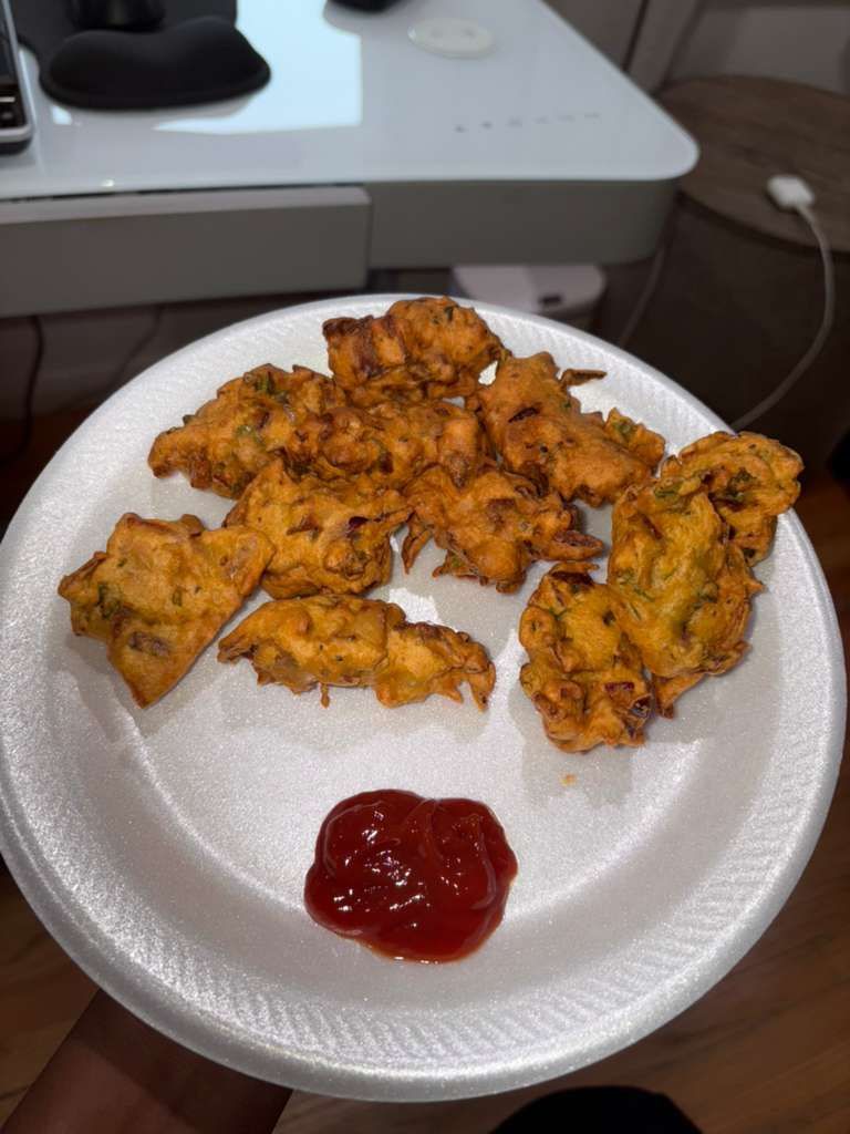 Plate of golden fried fritters with ketchup on a white table next to a keyboard