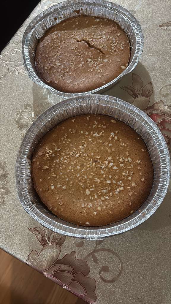 Two round foil cups of baked dessert on a patterned tablecloth